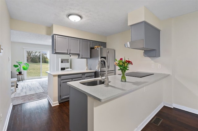 kitchen featuring dark wood-style floors, gray cabinets, stainless steel fridge, a peninsula, and black electric cooktop