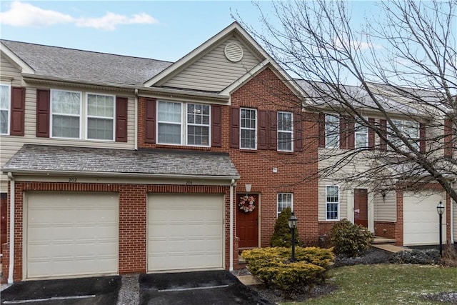 view of property featuring a garage, roof with shingles, driveway, and brick siding