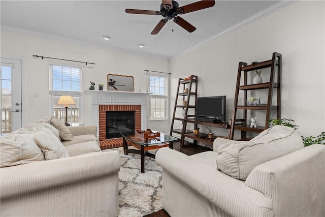 living area with ornamental molding, a healthy amount of sunlight, a fireplace, and wood finished floors