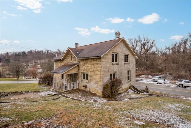 rear view of property with stone siding and a chimney