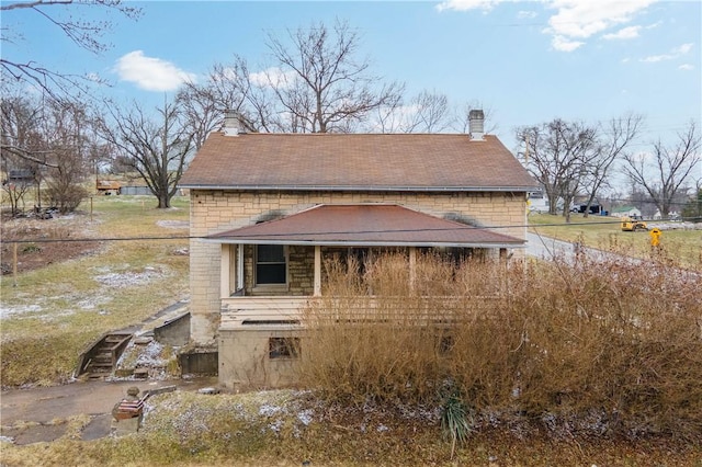 exterior space with stone siding and a chimney