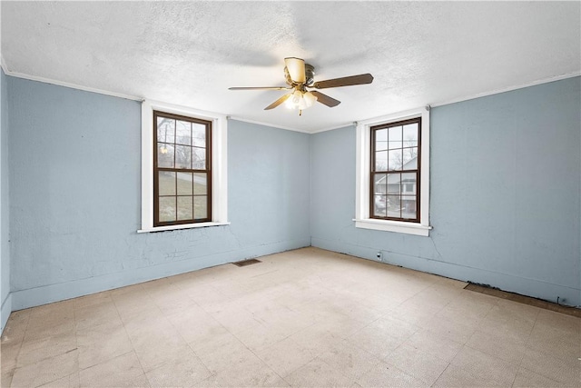 spare room featuring crown molding, a textured ceiling, a wealth of natural light, and tile patterned floors