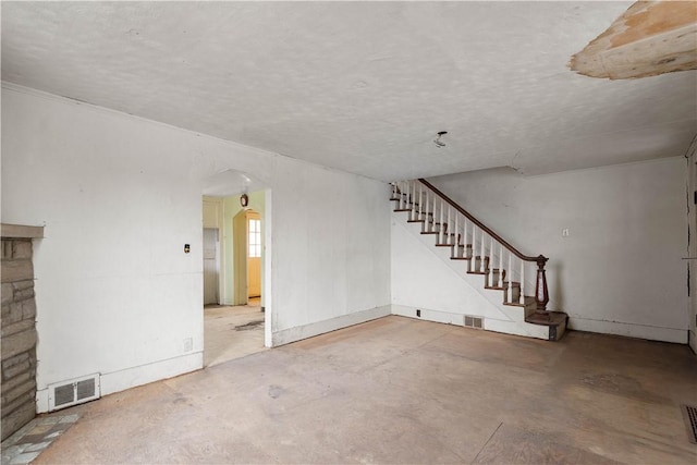 unfurnished living room with arched walkways, concrete floors, stairway, and visible vents