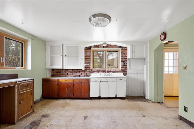 kitchen with arched walkways, light floors, light countertops, white cabinets, and a sink