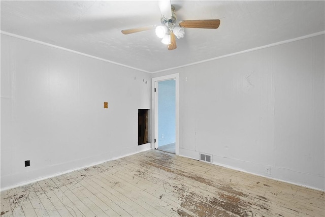 empty room with hardwood / wood-style flooring, visible vents, ornamental molding, and a ceiling fan