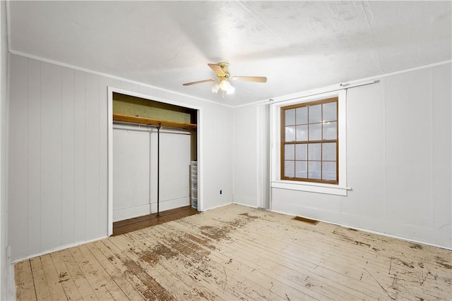 unfurnished bedroom with visible vents, hardwood / wood-style flooring, ceiling fan, ornamental molding, and a closet