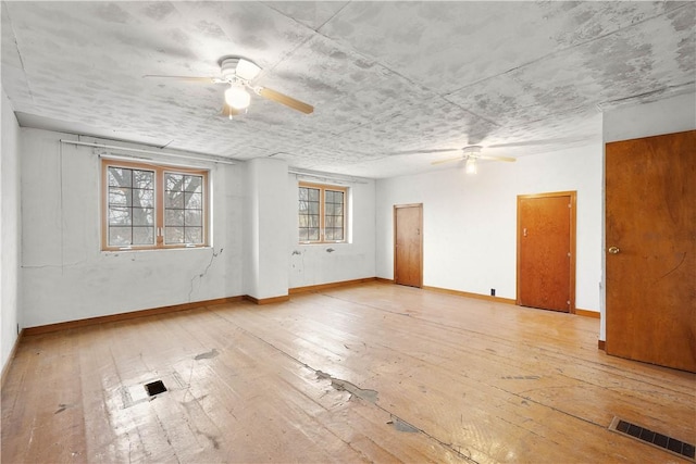 empty room with light wood finished floors, baseboards, visible vents, and a ceiling fan