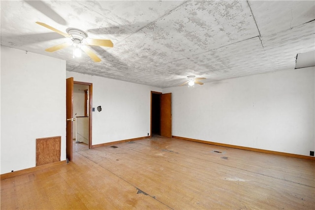 spare room featuring baseboards, ceiling fan, and light wood-style floors