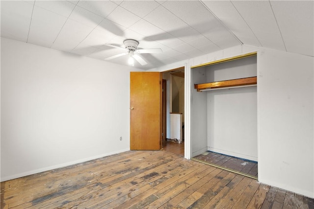 unfurnished bedroom featuring a closet, hardwood / wood-style floors, vaulted ceiling, ceiling fan, and baseboards