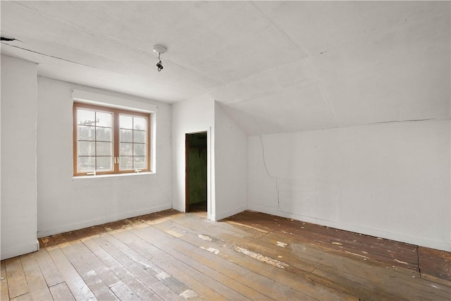 additional living space with hardwood / wood-style flooring, baseboards, and vaulted ceiling