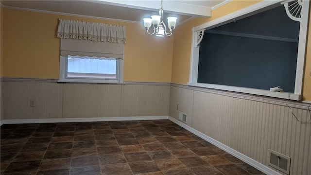 unfurnished room with stone finish flooring, visible vents, a notable chandelier, and wainscoting