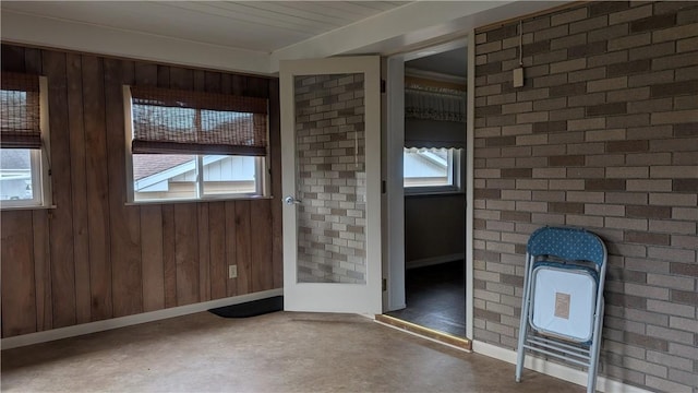 doorway featuring finished concrete flooring, brick wall, and a healthy amount of sunlight