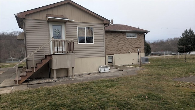 back of house with central AC, a yard, brick siding, and fence