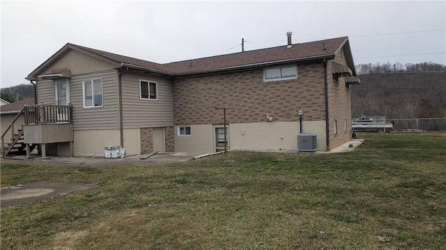 rear view of house featuring brick siding, cooling unit, a patio, and a yard