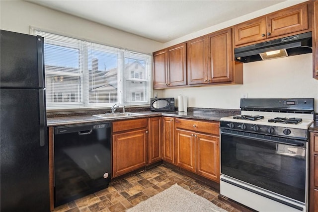 kitchen with dark countertops, brown cabinetry, a sink, under cabinet range hood, and black appliances