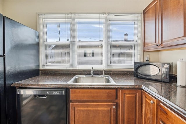 kitchen featuring brown cabinetry, dark countertops, a sink, and black appliances