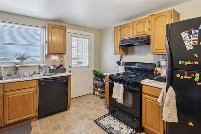 kitchen featuring a sink, black appliances, light countertops, and under cabinet range hood