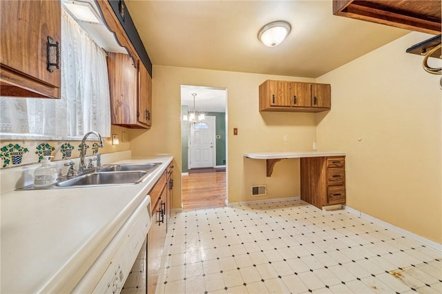 kitchen with a sink, visible vents, light countertops, light floors, and brown cabinetry