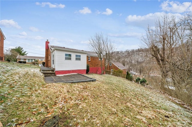 rear view of property featuring a patio, a chimney, and a lawn