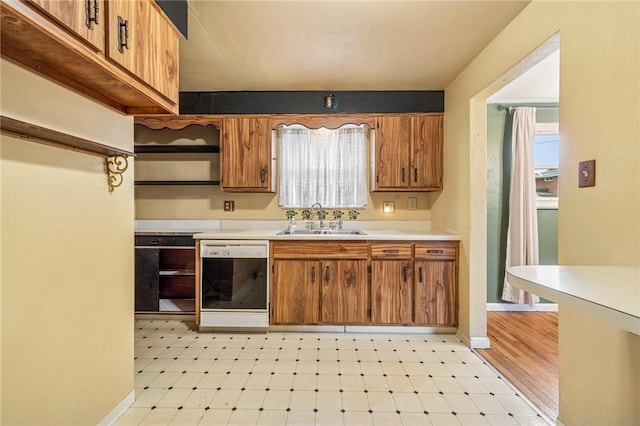 kitchen featuring dishwashing machine, light countertops, light floors, open shelves, and a sink