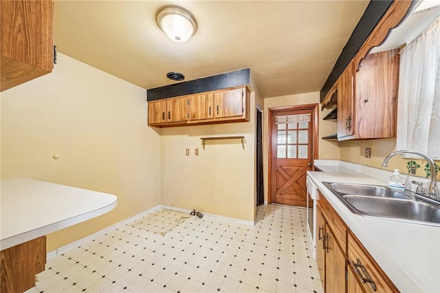 kitchen with light floors, light countertops, visible vents, a sink, and baseboards