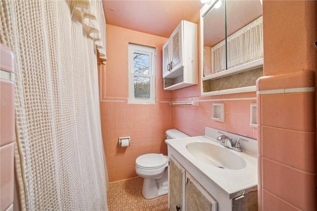 bathroom with a shower with shower curtain, toilet, tile patterned floors, vanity, and tile walls