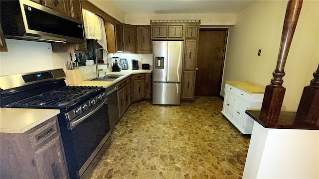 kitchen with stone finish floor, appliances with stainless steel finishes, and a sink