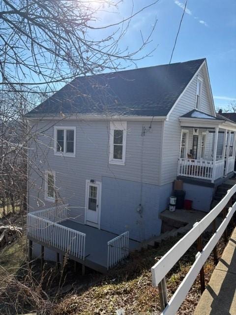 view of home's exterior with a shingled roof and a wooden deck