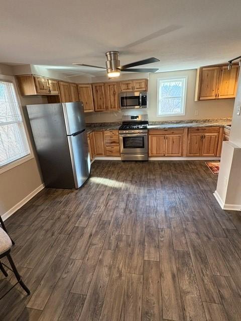 kitchen with appliances with stainless steel finishes, dark wood-style flooring, baseboards, and a ceiling fan