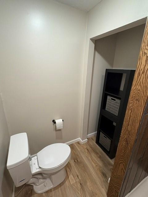 bathroom featuring wood finished floors, toilet, and baseboards