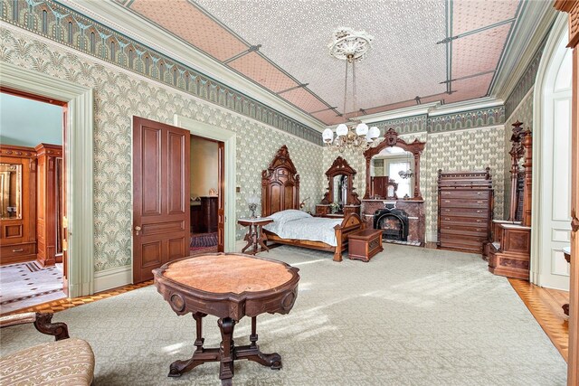 bedroom featuring wallpapered walls, a fireplace, ornamental molding, and an inviting chandelier