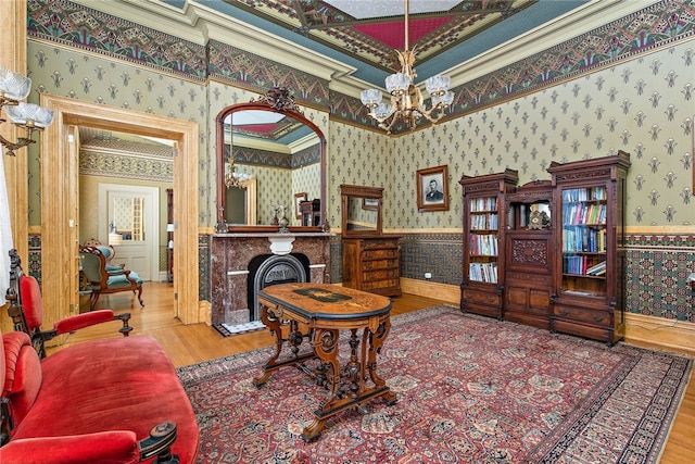 living area featuring wallpapered walls, a chandelier, a wainscoted wall, and wood finished floors