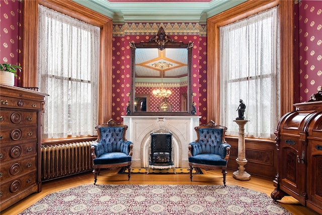 living area featuring wood finished floors, radiator, a fireplace, and wallpapered walls