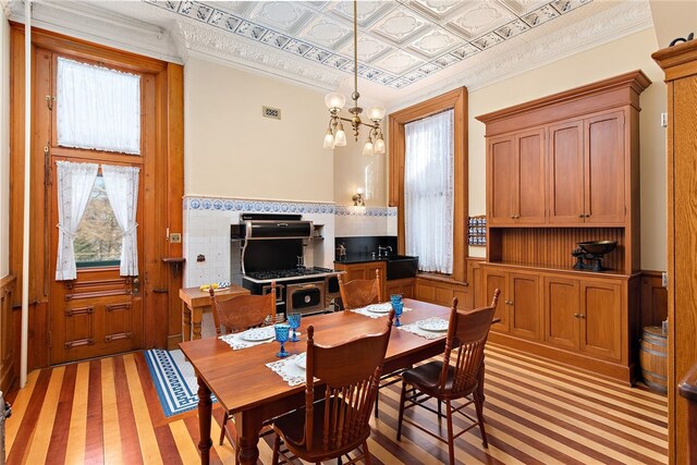 dining area featuring visible vents, wainscoting, an ornate ceiling, ornamental molding, and a chandelier