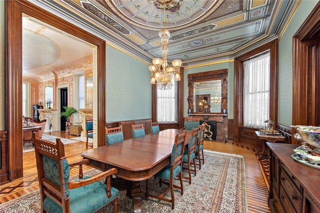 dining room with a wainscoted wall, a fireplace, an ornate ceiling, and crown molding