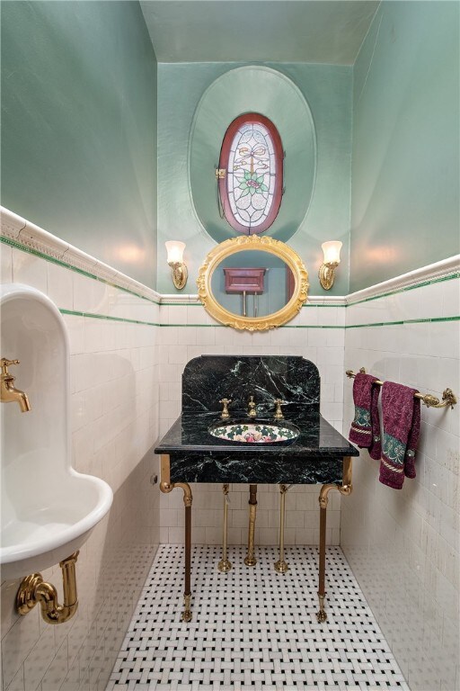 bathroom with tile patterned flooring, wainscoting, a sink, and tile walls