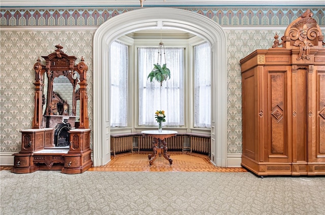 living area featuring baseboards, arched walkways, and wallpapered walls