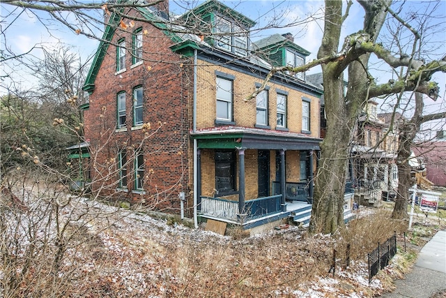 view of front of house featuring brick siding and a porch