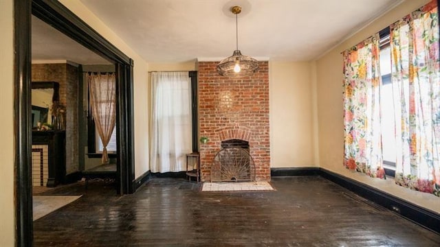 unfurnished living room featuring a brick fireplace, baseboards, and hardwood / wood-style flooring