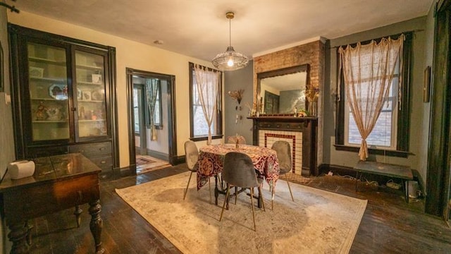 dining area featuring a brick fireplace, baseboards, and wood finished floors