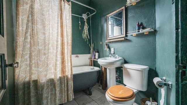 bathroom featuring toilet, a wainscoted wall, tile patterned flooring, shower / bath combo with shower curtain, and a sink