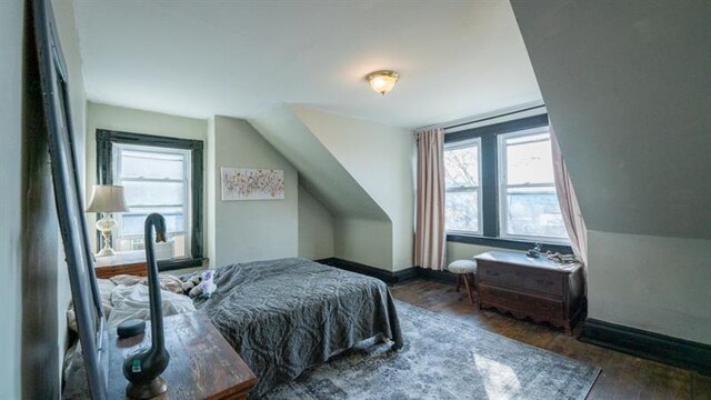 bedroom with lofted ceiling, multiple windows, baseboards, and wood finished floors