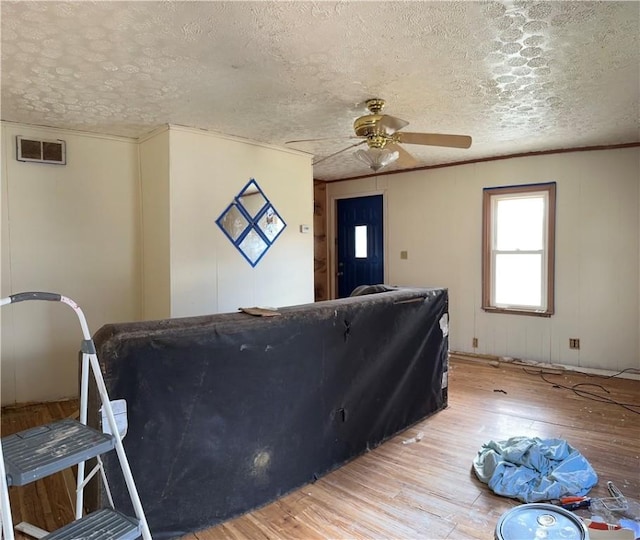 living area featuring visible vents, crown molding, and light wood finished floors