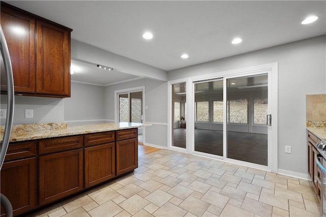 kitchen featuring a peninsula, baseboards, light stone counters, and recessed lighting