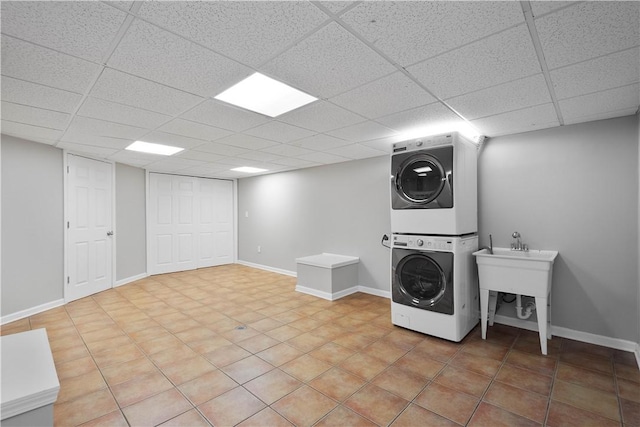 washroom featuring a sink, laundry area, baseboards, and stacked washer / drying machine