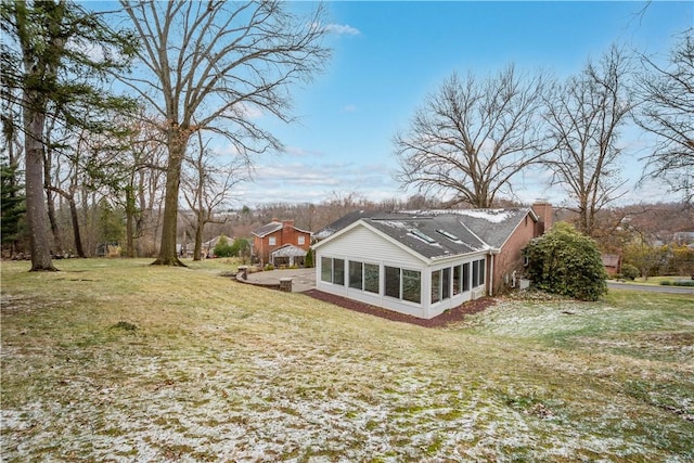 exterior space with a sunroom, a chimney, and a yard