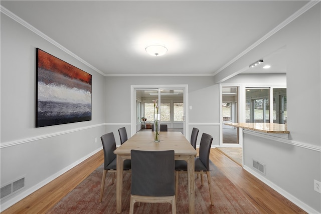 dining space with crown molding, visible vents, and wood finished floors