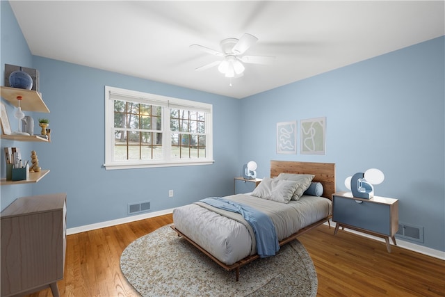 bedroom with baseboards, visible vents, and wood finished floors