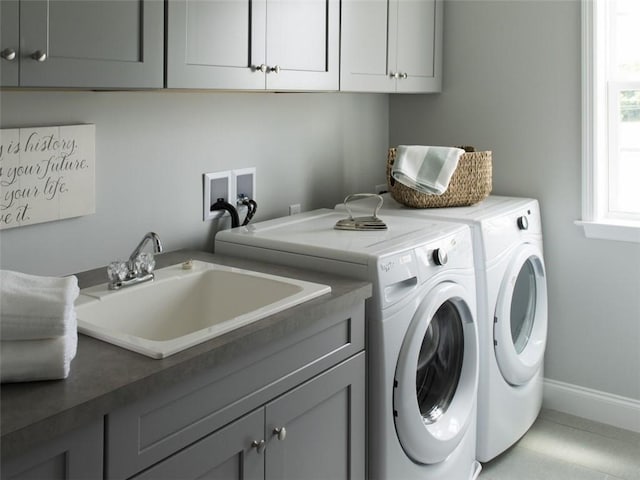 laundry area with cabinet space, baseboards, a sink, and washing machine and clothes dryer