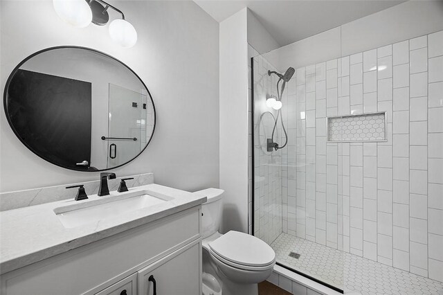 bathroom featuring tiled shower, vanity, and toilet